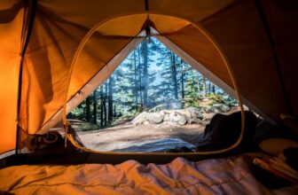 A well-organized camping setup with essential gear laid out, including a tent, backpack, and cooking equipment in a natural outdoor setting.
