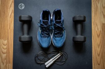 A well-organized home gym with various fitness equipment like dumbbells, a yoga mat, and resistance bands in a cozy space.