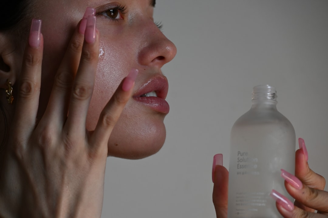 A close-up of a person's hands applying skincare products on their face, showcasing a variety of skincare items like serums and moisturizers.