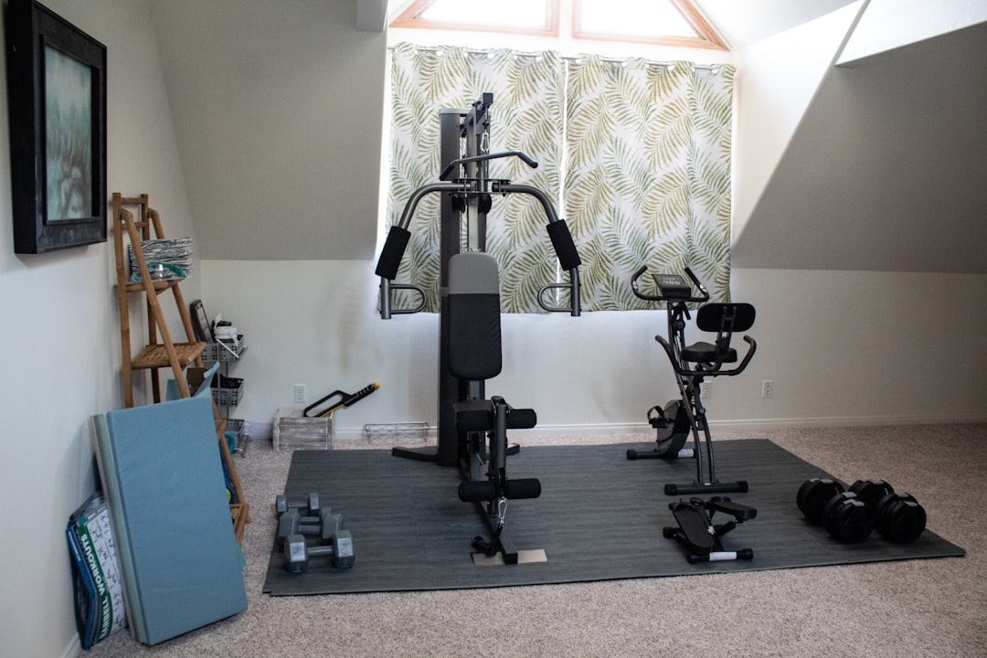 A cozy home gym with basic fitness equipment like dumbbells, a yoga mat, and resistance bands in a well-lit room.