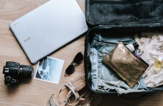 A neatly organized carry-on suitcase with travel essentials like clothing, toiletries, and tech gadgets visible, set against a backdrop of an airport or travel setting.